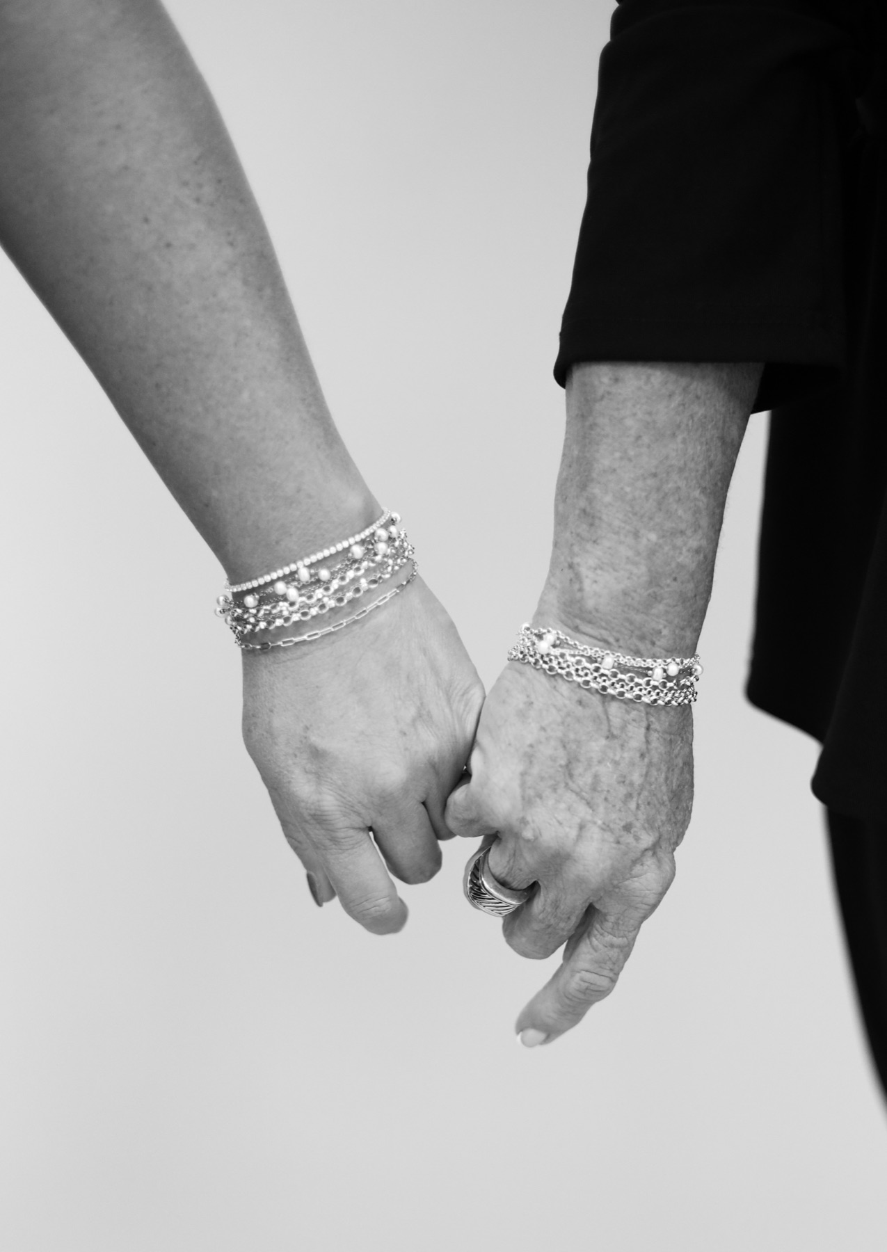 Two hands side by side wearing stacked welded bracelets